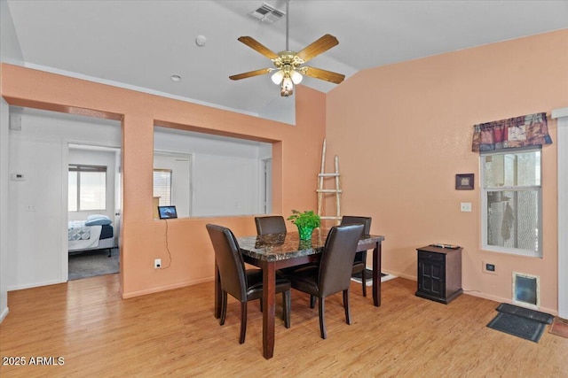 dining space with visible vents, baseboards, ceiling fan, light wood-style floors, and lofted ceiling