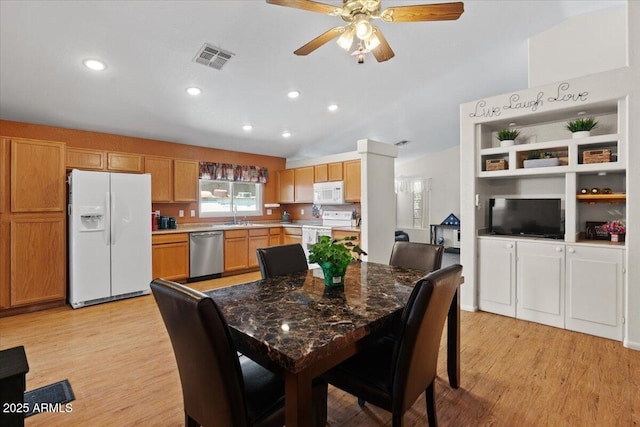 dining room with a ceiling fan, vaulted ceiling, visible vents, and light wood-style floors
