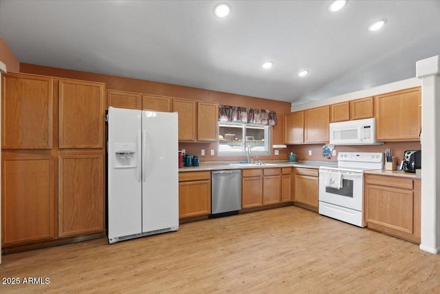 kitchen featuring light wood finished floors, light countertops, a sink, and white appliances