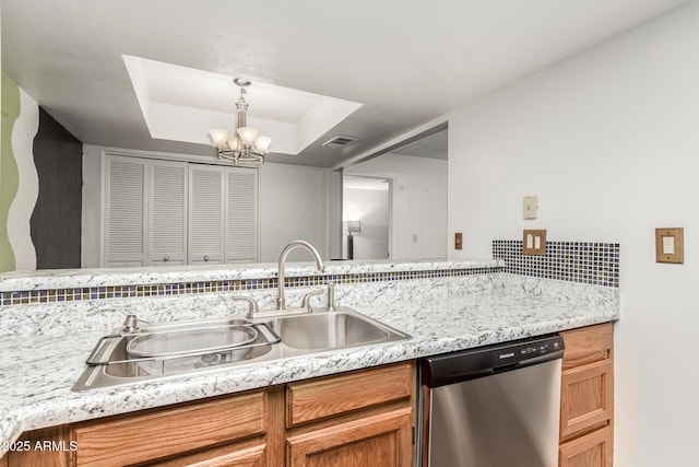 kitchen with tasteful backsplash, a tray ceiling, hanging light fixtures, stainless steel dishwasher, and sink