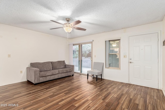 living room featuring ceiling fan, a textured ceiling, and dark hardwood / wood-style flooring