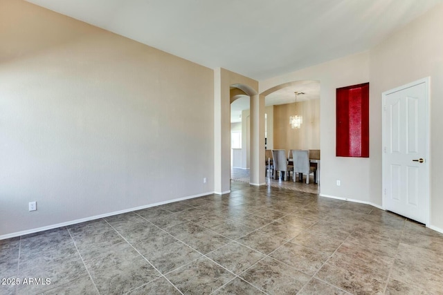 11664 W Eagle Ct, Surprise, AZ 85378 - tiled empty room featuring baseboards, arched walkways, and a notable chandelier