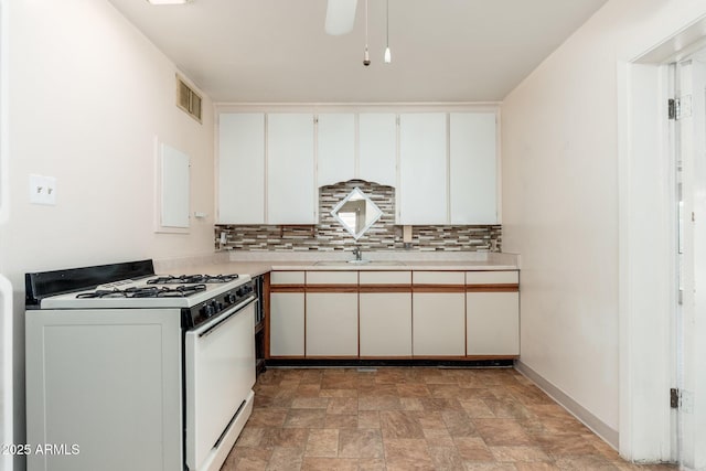 2002 W Whitton Ave, Phoenix, AZ 85015 - kitchen featuring white range with gas cooktop, stone finish floors, light countertops, decorative backsplash, and white cabinets