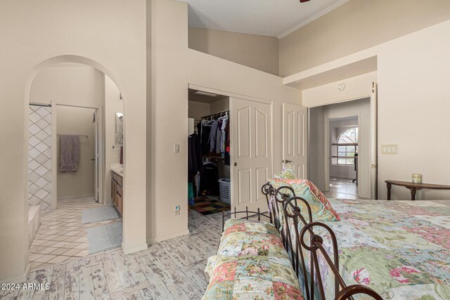 tiled bedroom featuring vaulted ceiling, ensuite bathroom, a spacious closet, and a closet