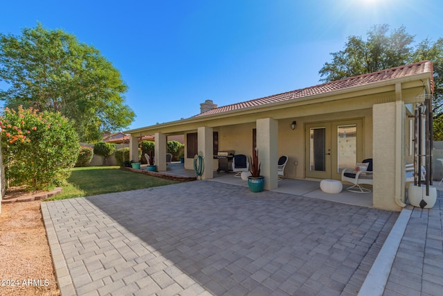 back of property with a lawn and a patio