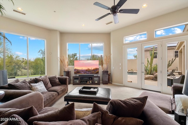 living area with light colored carpet, a wealth of natural light, visible vents, and recessed lighting