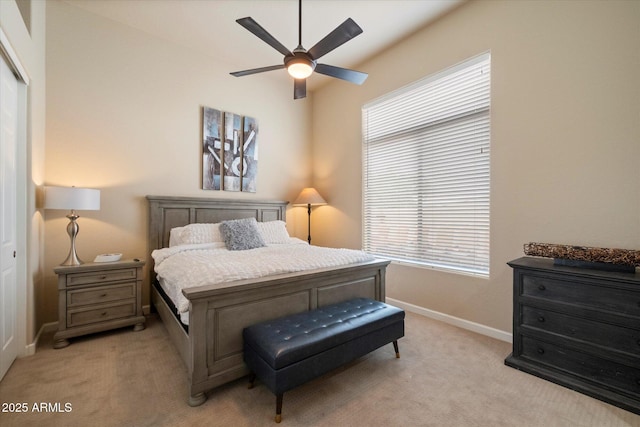 bedroom with ceiling fan, light carpet, a closet, and baseboards