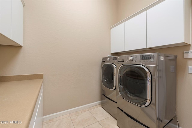 clothes washing area featuring cabinet space, washing machine and clothes dryer, baseboards, and light tile patterned flooring