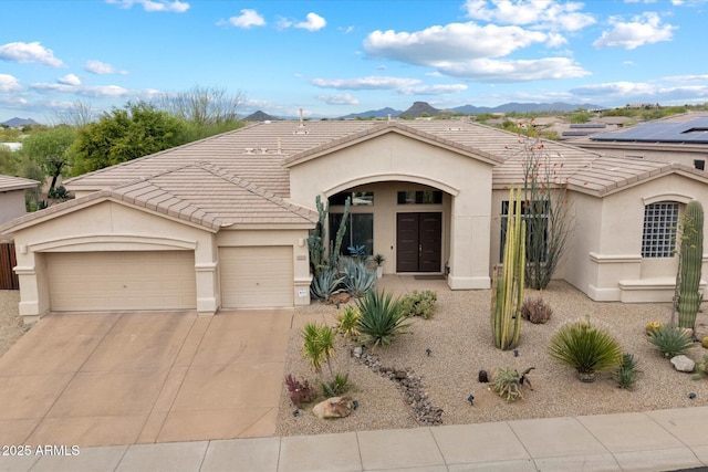 view of front of house with stucco siding, an attached garage, a tile roof, driveway, and a mountain view