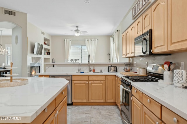 755 E Orchid Ln, Gilbert, AZ 85296 - kitchen featuring light brown cabinets, ceiling fan with notable chandelier, sink, a fireplace, and stainless steel appliances