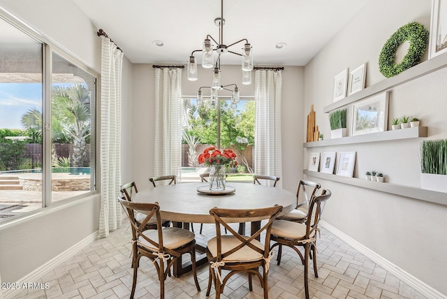 dining space featuring baseboards, brick floor, and a chandelier