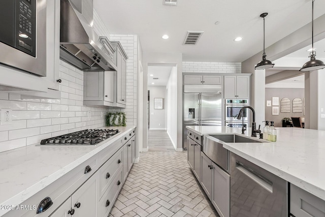 kitchen with visible vents, gray cabinetry, wall chimney range hood, and stainless steel appliances