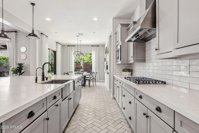 kitchen with wall chimney exhaust hood, tasteful backsplash, gray cabinetry, and stainless steel appliances