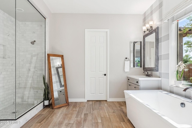 full bath with vanity, baseboards, a tile shower, and wood finished floors
