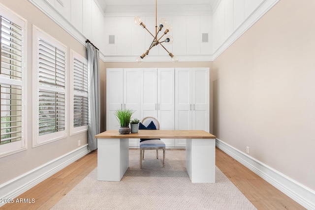 office space with crown molding, baseboards, a chandelier, and light wood-style floors
