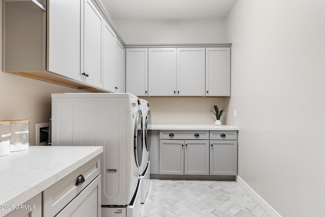 laundry area featuring baseboards, cabinet space, and washer and clothes dryer