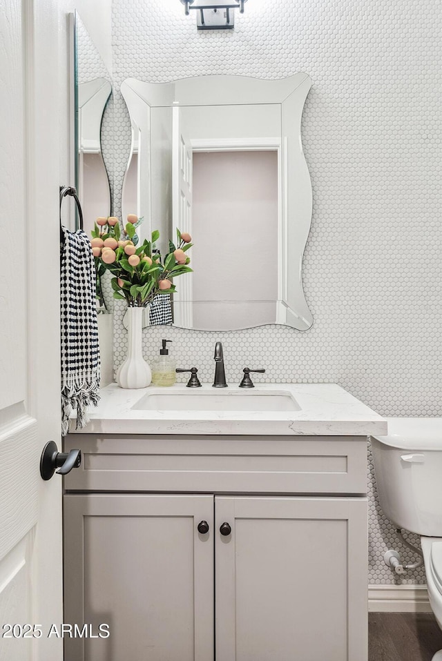 bathroom with vanity, backsplash, toilet, and wood finished floors