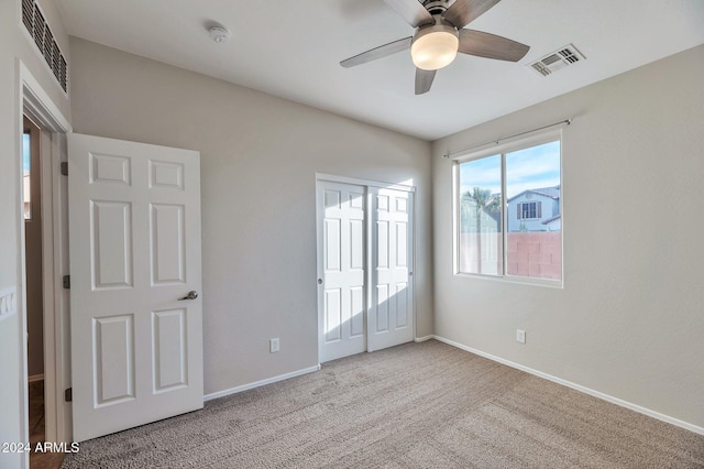 unfurnished bedroom featuring ceiling fan, a closet, and light colored carpet