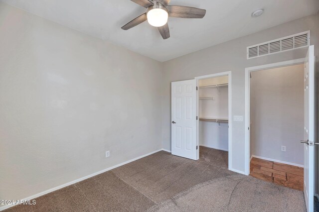 unfurnished bedroom with a walk in closet, ceiling fan, a closet, and dark carpet