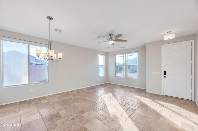 spare room featuring ceiling fan with notable chandelier