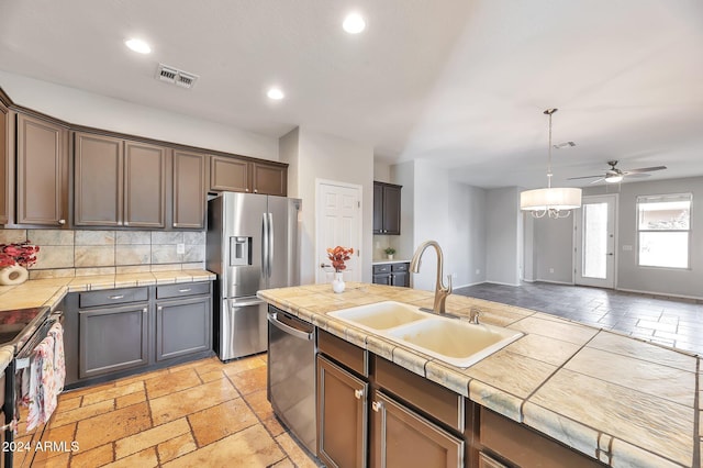 kitchen featuring tile countertops, stainless steel appliances, tasteful backsplash, and sink