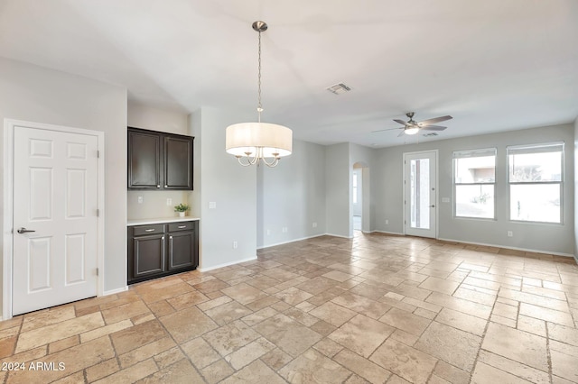 interior space featuring dark brown cabinetry, hanging light fixtures, and ceiling fan with notable chandelier