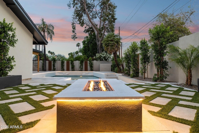 yard at dusk featuring an outdoor fire pit, a patio, and a fenced backyard