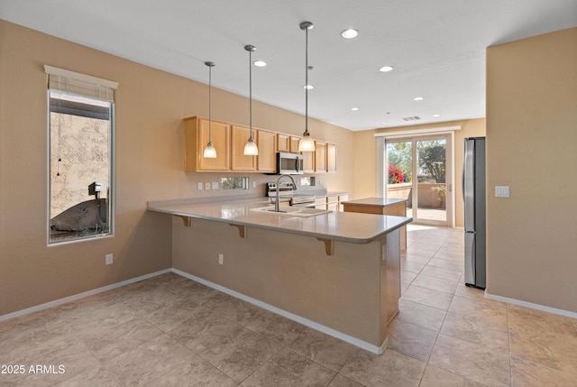 kitchen with sink, decorative light fixtures, light brown cabinets, appliances with stainless steel finishes, and kitchen peninsula