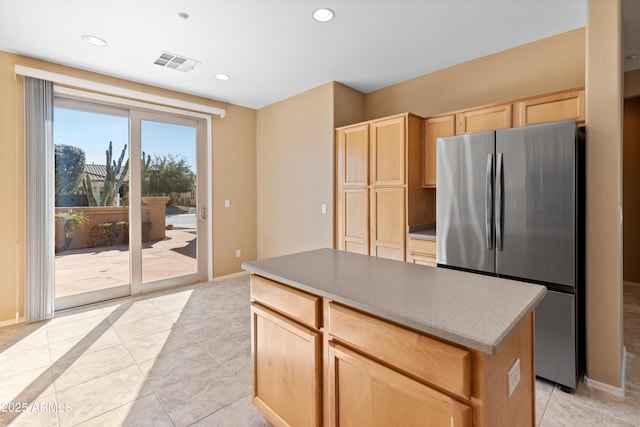 kitchen with stainless steel fridge, a center island, and light brown cabinetry