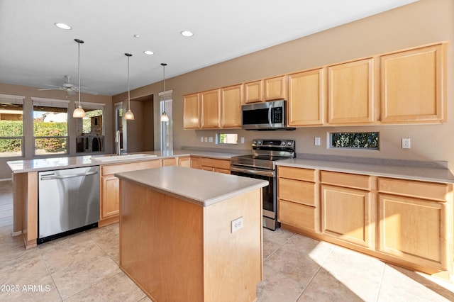 kitchen featuring decorative light fixtures, sink, kitchen peninsula, stainless steel appliances, and light brown cabinets