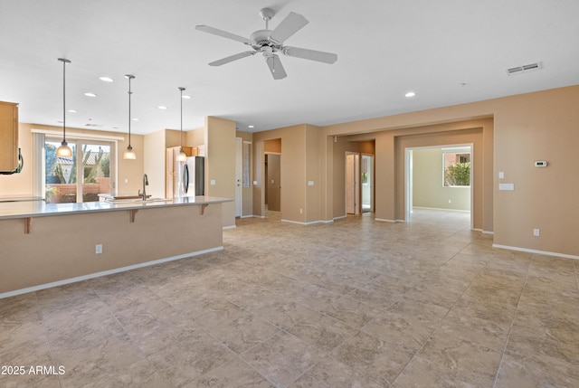 unfurnished living room featuring sink, plenty of natural light, and ceiling fan