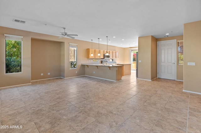 unfurnished living room featuring ceiling fan and a healthy amount of sunlight