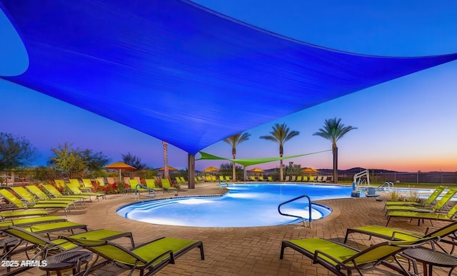 pool at dusk featuring a patio area