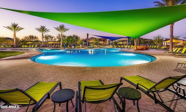 pool at dusk featuring a patio area