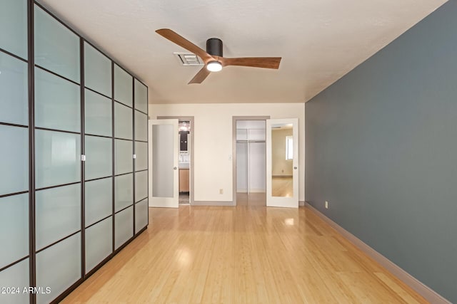 unfurnished bedroom with ceiling fan, light wood-type flooring, french doors, and a closet