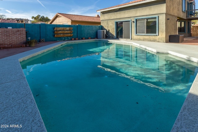 view of swimming pool featuring a patio and central air condition unit