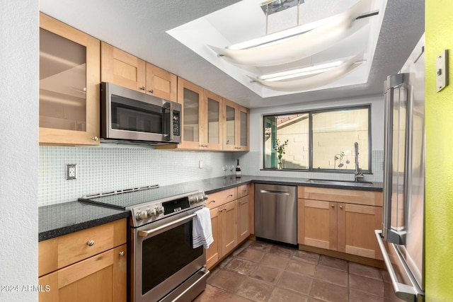 kitchen featuring tasteful backsplash, sink, appliances with stainless steel finishes, and a tray ceiling