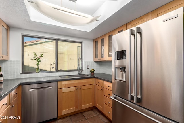 kitchen featuring dark tile patterned flooring, backsplash, sink, and appliances with stainless steel finishes