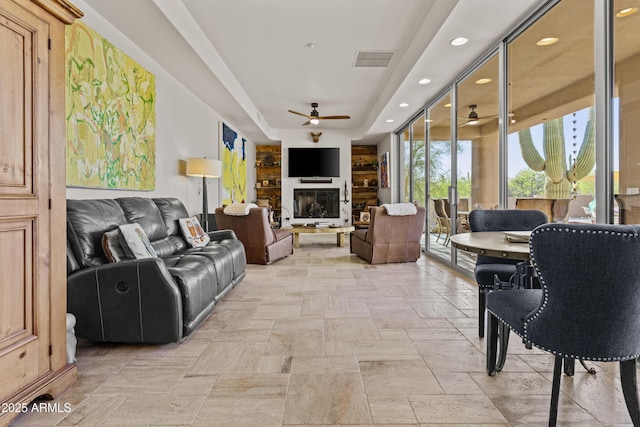living area featuring ceiling fan, a raised ceiling, stone tile floors, recessed lighting, and visible vents
