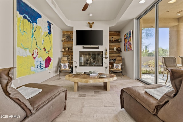 living room with a glass covered fireplace, a ceiling fan, recessed lighting, and visible vents