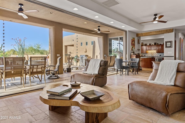 living room featuring stone tile floors, a ceiling fan, visible vents, and recessed lighting