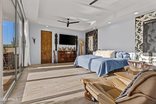 bedroom featuring recessed lighting, ceiling fan, wood finished floors, and a tray ceiling
