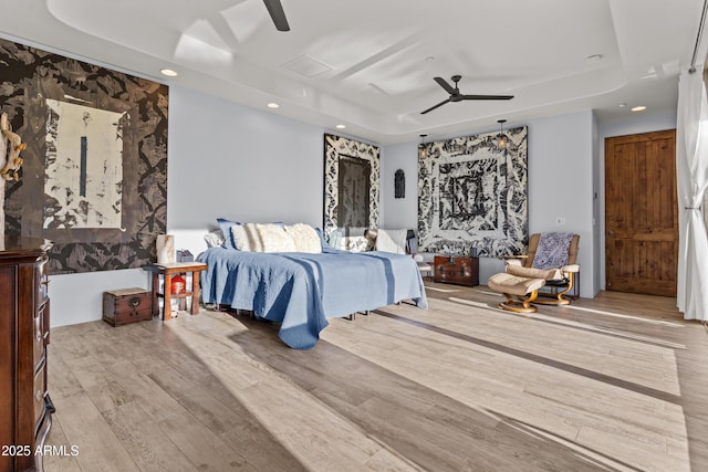 bedroom featuring a ceiling fan, a tray ceiling, recessed lighting, and wood finished floors
