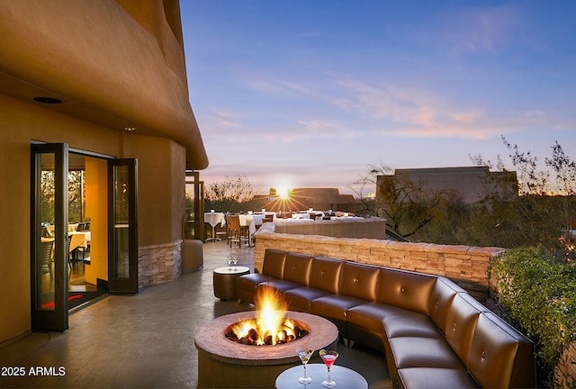 patio terrace at dusk with outdoor dining space and an outdoor living space with a fire pit