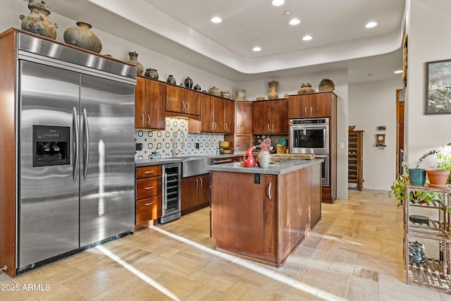 kitchen featuring a kitchen island, backsplash, appliances with stainless steel finishes, beverage cooler, and recessed lighting