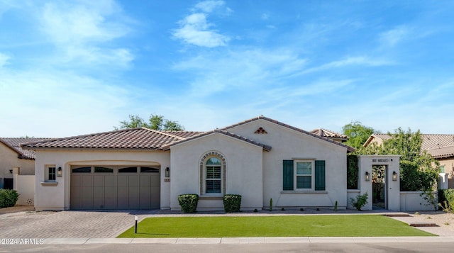 mediterranean / spanish-style house with a garage and a front lawn