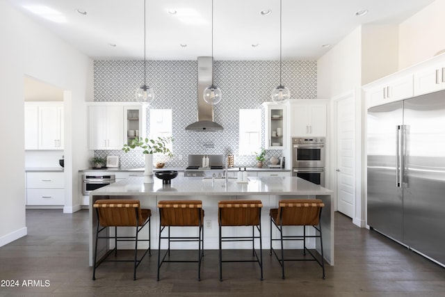 kitchen featuring a kitchen bar, stainless steel appliances, hanging light fixtures, and a center island with sink