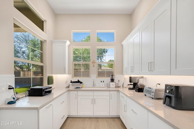 kitchen featuring white cabinetry, sink, and light hardwood / wood-style flooring