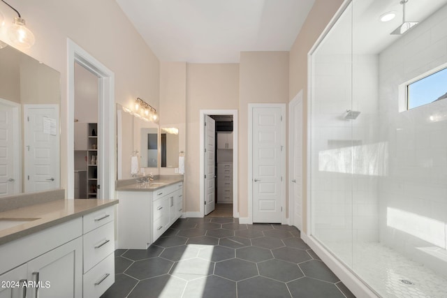 bathroom with tile patterned floors, vanity, and a tile shower