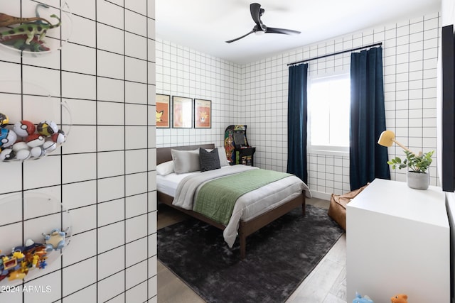 bedroom featuring ceiling fan and tile walls